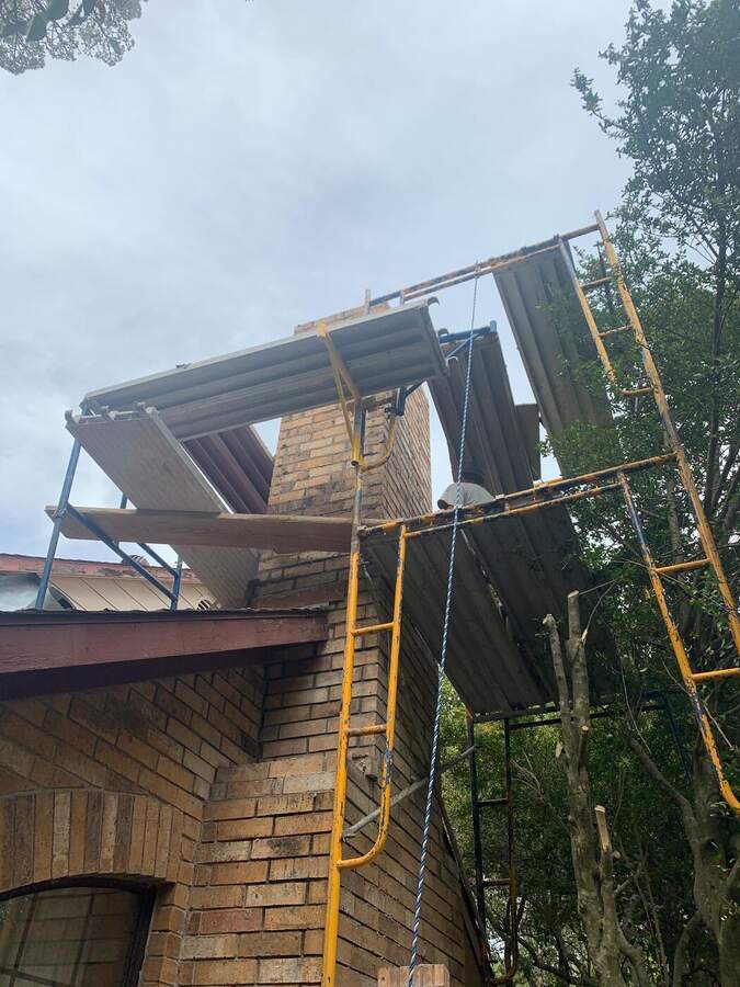 Before: deteriorated brick chimney under scaffolding