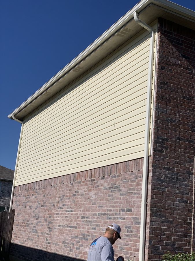 Two-story Denton home with new cream siding above the brick