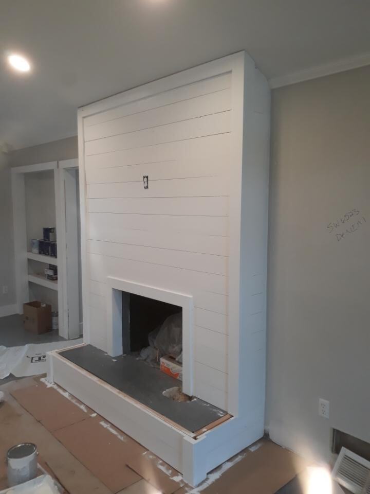 Floor-to-ceiling shiplap fireplace with a raised hearth
