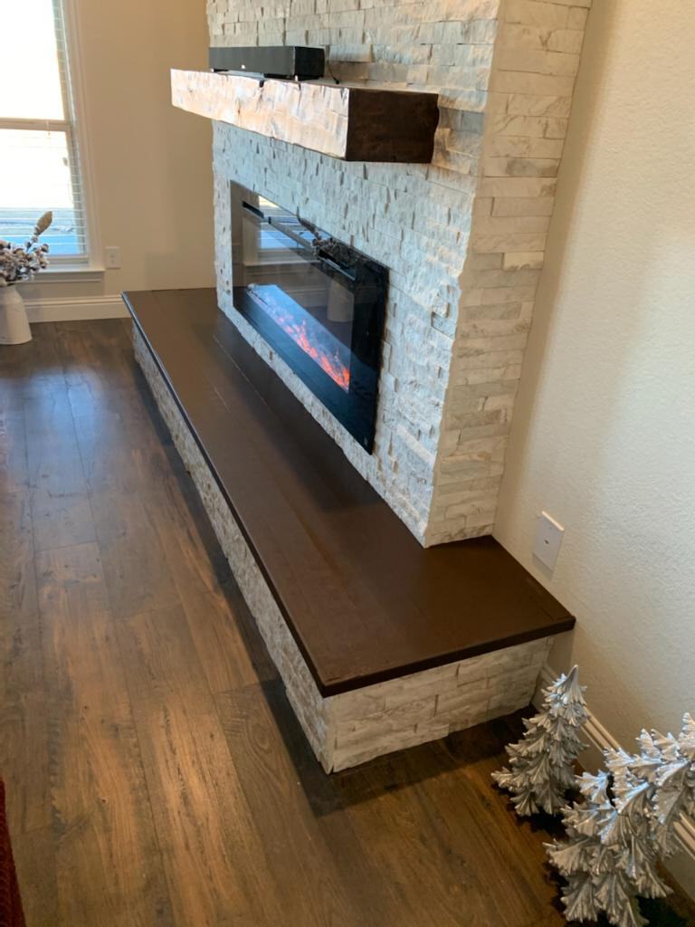 Dark wood hearth bench on a white stone fireplace