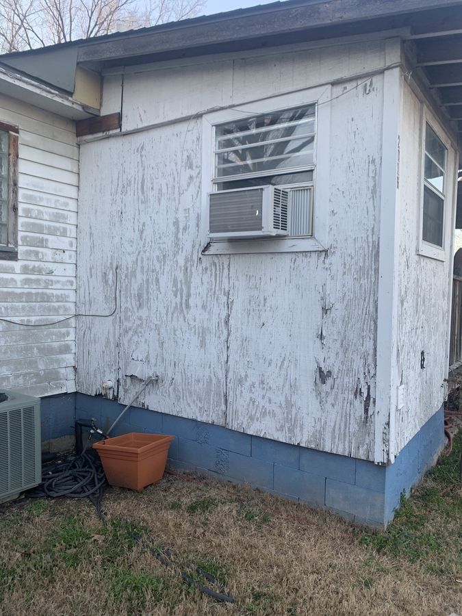 Whole-house re-side, cream to navy in Downtown Garland — Before — failing lap siding