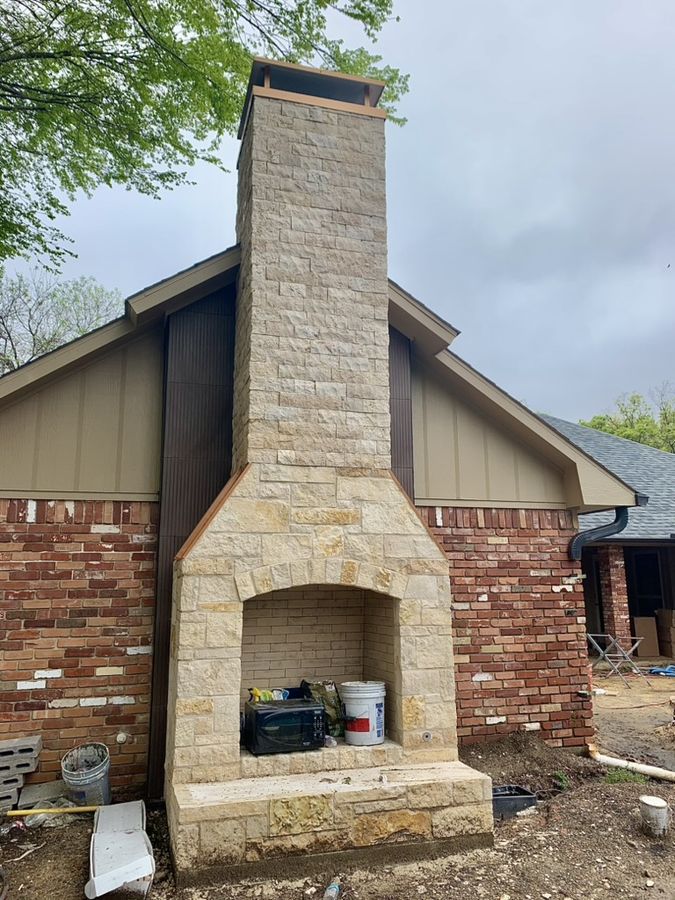 Custom cut-stone outdoor fireplace and chimney beside a pool in Richardson
