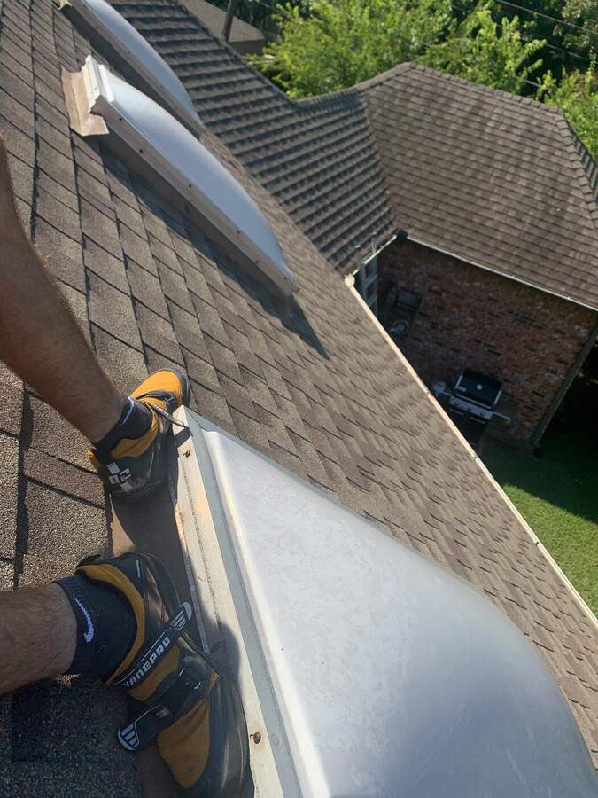Roofer's hand on a shingle ridge during a repair