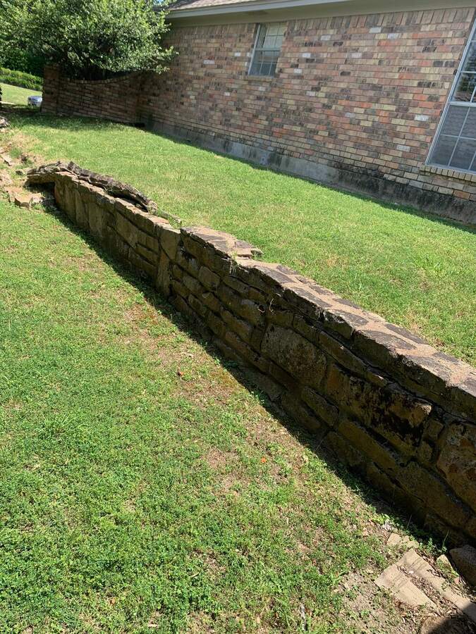 Before: leaning, crumbling stone retaining wall